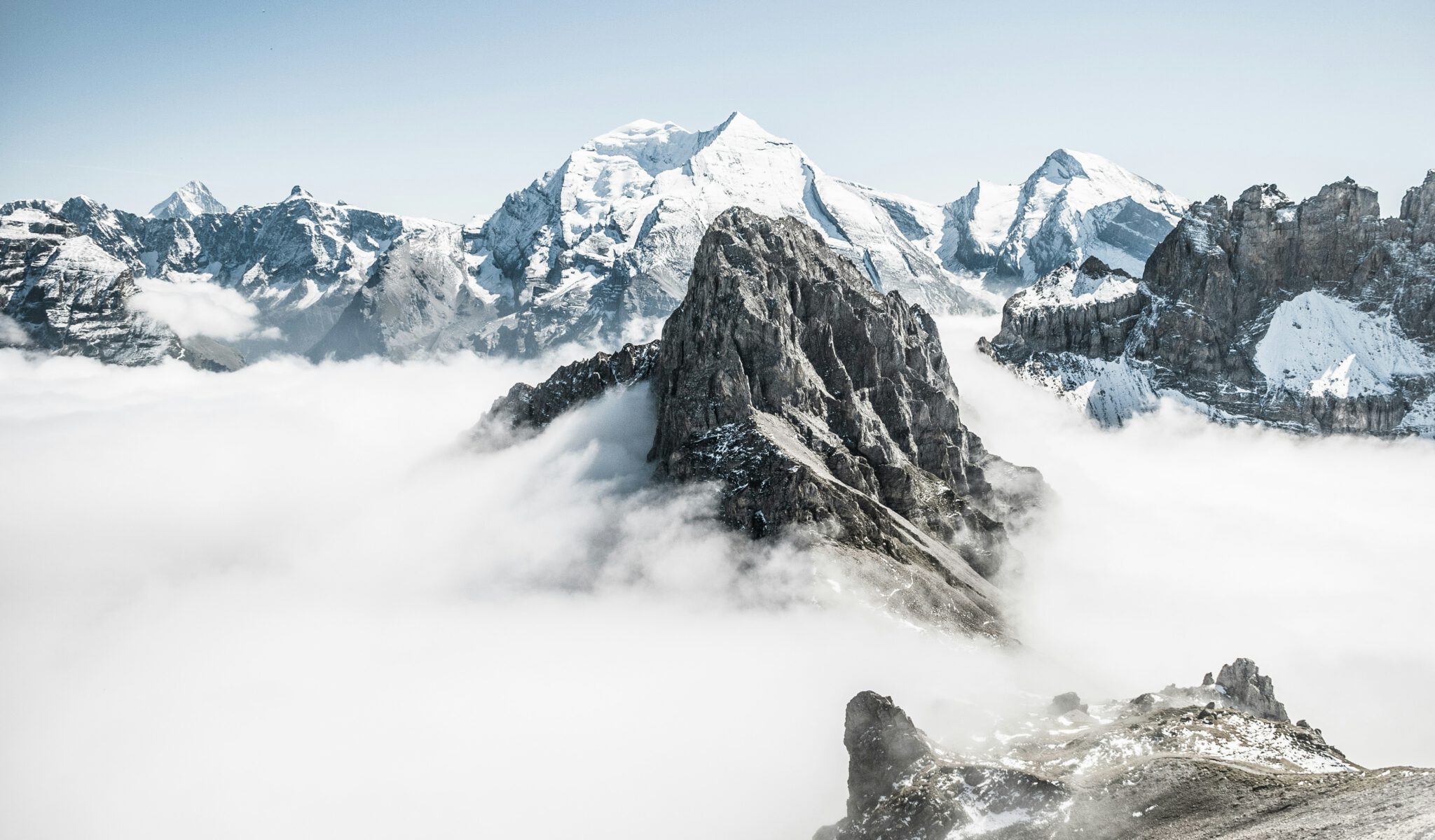 Snow-capped mountains peeking through clouds, bright and distant